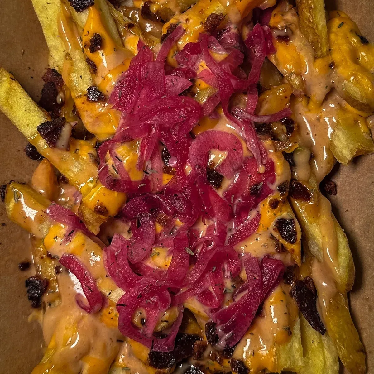 Bacon Cheese Fries desde arriba: patatas con salsa de queso, bacon y cebolla encurtida morada