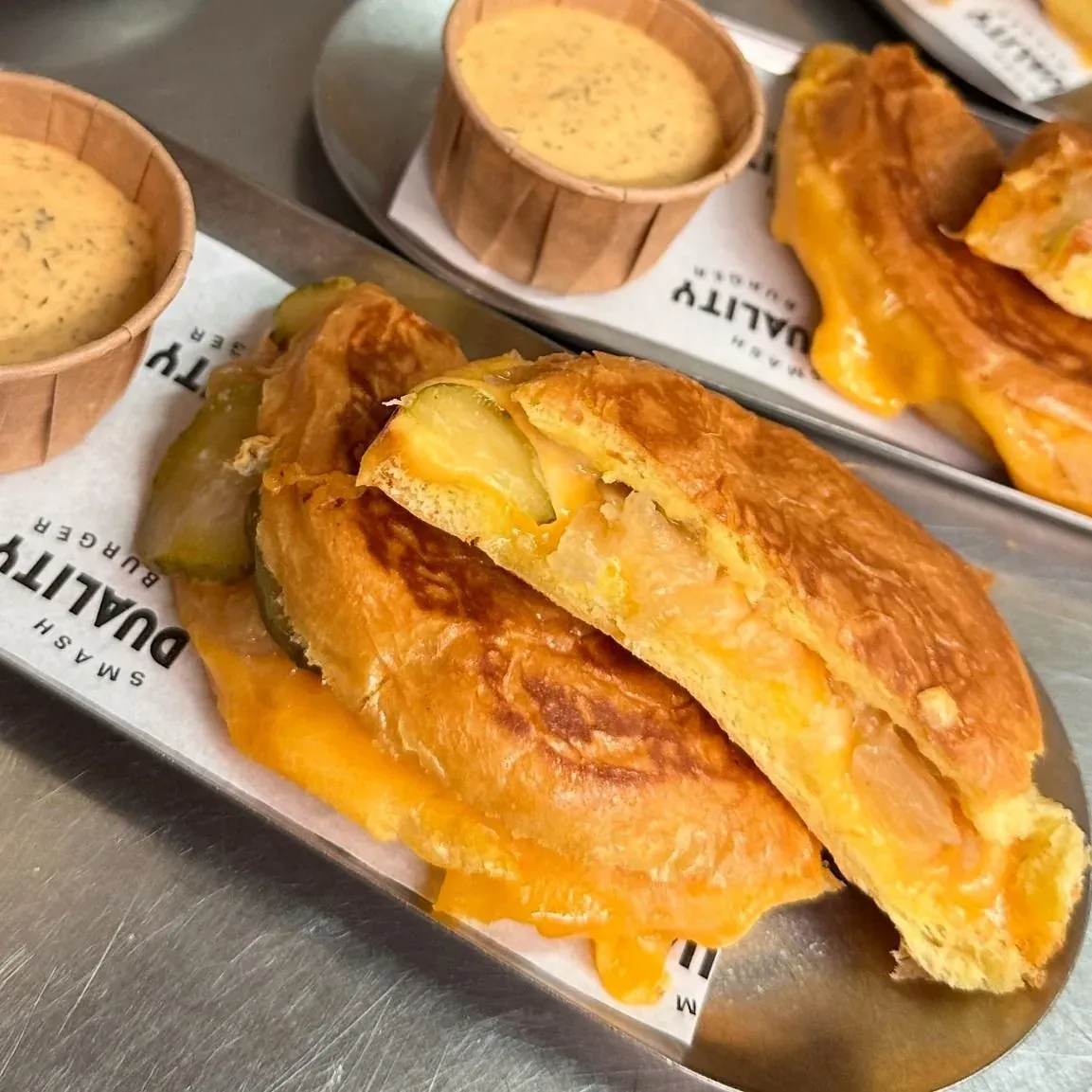 Cheese Slider abiertos con cheddar fundido y pepinillo, con salsa para mojar